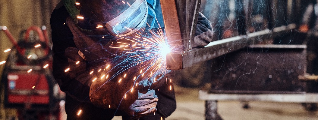 Man is working at metal factory, he is welding a piece of rail using special tools.