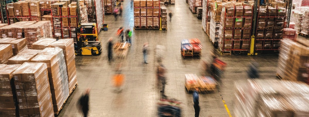 Warehouse bustling with activity as workers move pallets and goods efficiently throughout the large storage area