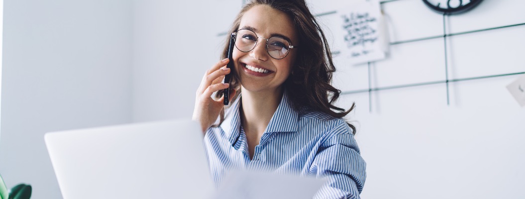 Young woman laughing while talking on cellphone in office